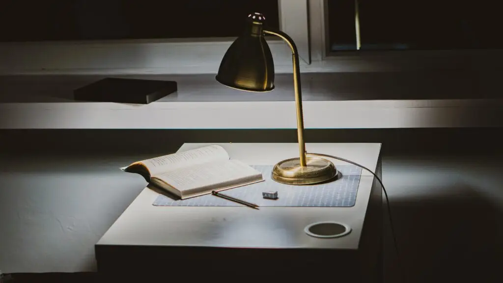 Cozy desk lamp lighting books on a study table at night