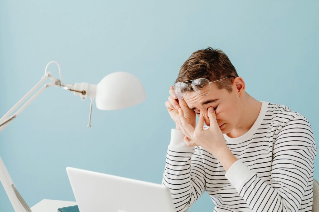 Man sitting at desk with tired eyes and hand on face due to poor lighting