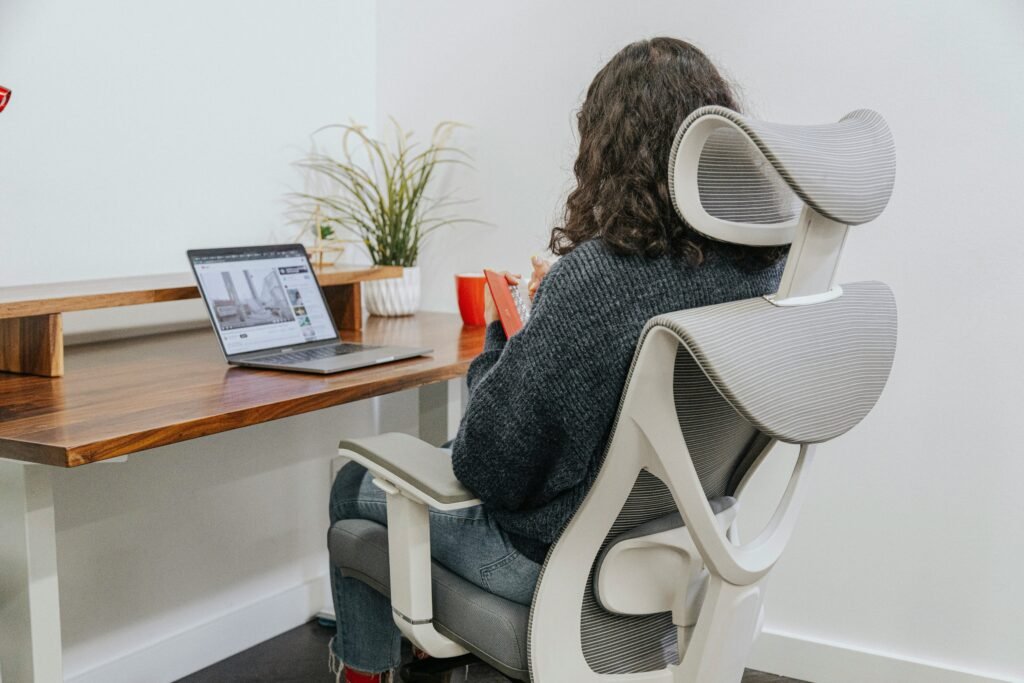 Student sitting on ergonomic chair with laptop at study desk