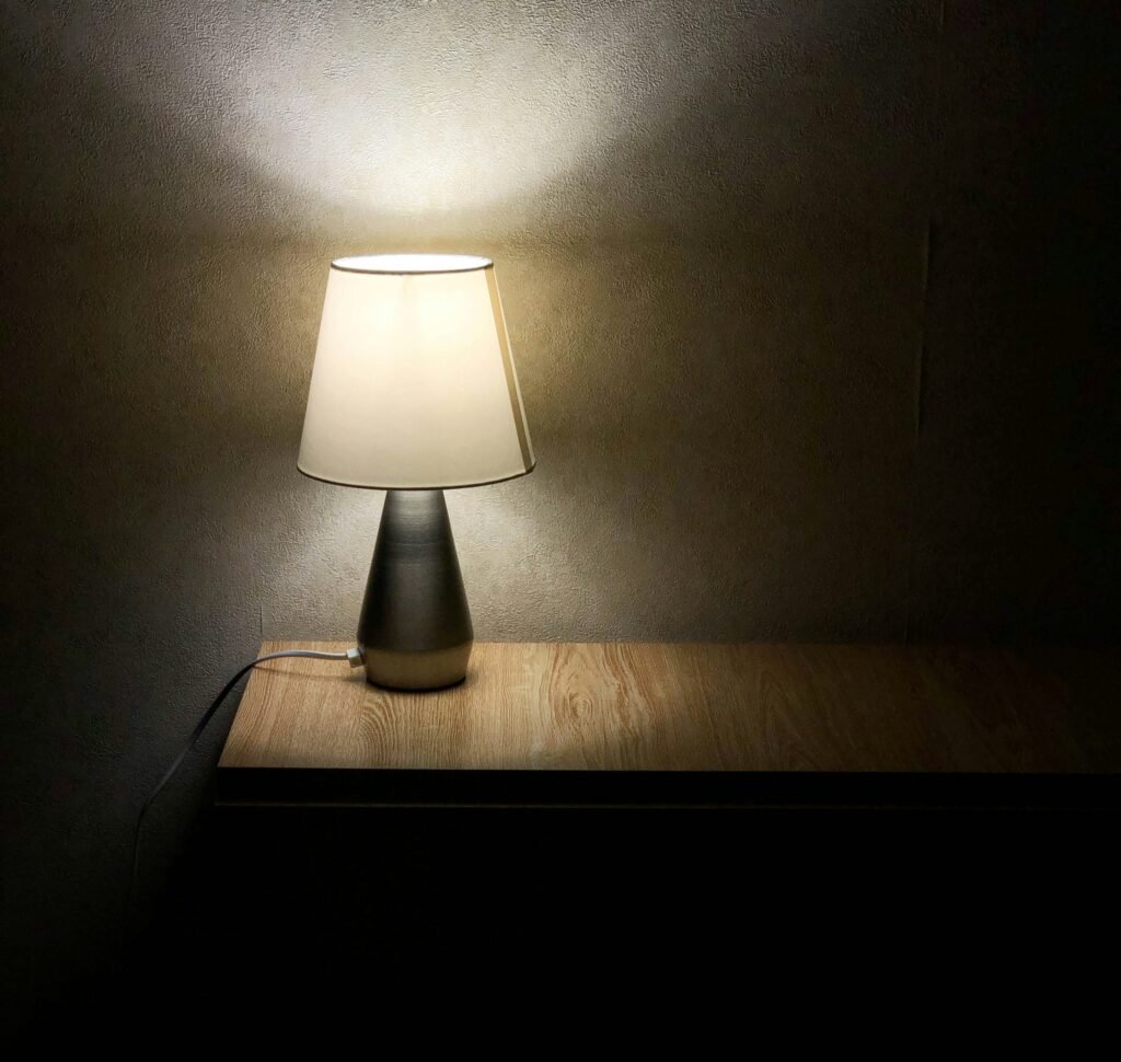 Vintage desk lamp glowing with warm yellow light in a dark room