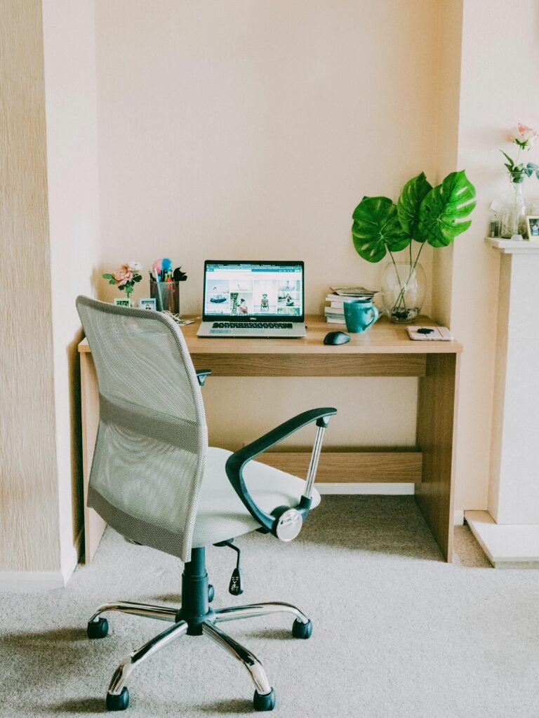 A cozy home office with a small desk, warm lighting, and a comfortable chair
